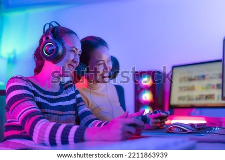 Asian woman gamer play online game with joystick and computer, E sport team at game center under they streaming they tournament