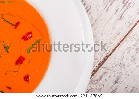 Close-up top-view picture of cold tasty tomato soup gazpacho with species on the wooden table in vegan caffee with copy place