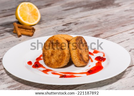 Close-up picture of three tasty cheesecakes with jam on the plate on the wooden table in caffee decorated with lemon and cinnamon, you want to eat them