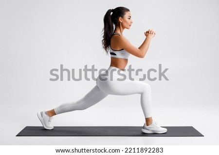 Fitness woman doing lunges exercises for leg muscle training. Active girl doing front forward one leg step lunge exercise Royalty-Free Stock Photo #2211892283