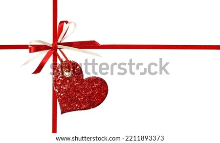 Crossed silk ribbons and a bow with glitter heart isolated on white background. Concept of present for Valentine’s Day.