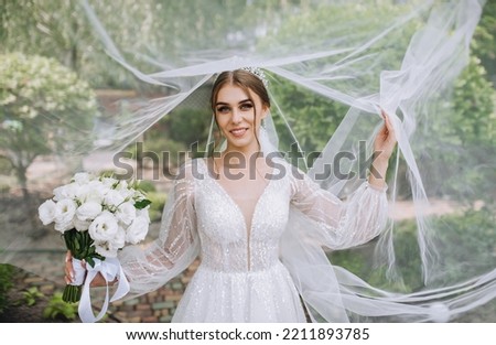 Portrait of a beautiful bride with a diadem on her head with a white long veil with a bouquet in her hands. wedding photography.