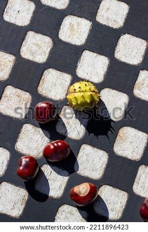 Chestnuts in the form of chess pieces on a chessboard. Autumn mood. vertical. Place for text.