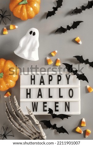 Happy Halloween lightbox sign board with pumpkin, bats and candy on a grey background.