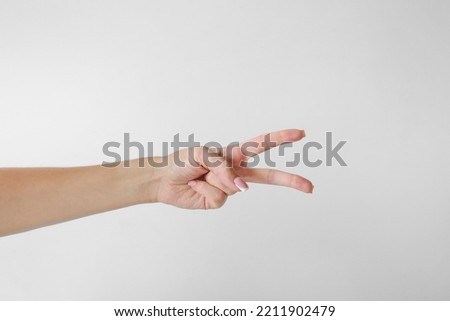 Woman hand holding two fingers on a white background