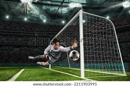 Soccer goalkeeper that makes a great save and avoids a goal during a match at the stadium Royalty-Free Stock Photo #2211903995