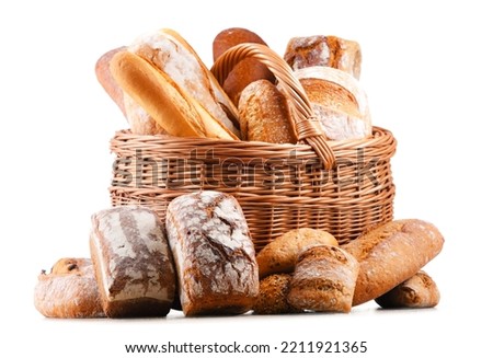Wicker basket with assorted bakery products including loafs of bread and rolls over white background