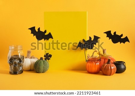yellow plate mock-up and halloween decor on a bright yellow background, candles in a glass, homemade pumpkins, felt bats, space for text, advertising
