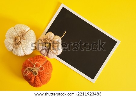 mocap black plate and halloween decor on a bright yellow background, knitted and fabric homemade pumpkins for holiday decoration, place for text, advertising, invitation