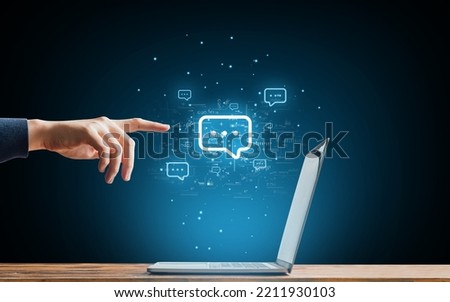 The concept of communication in chats and instant messengers in Internet resources and social networks. The character touches the hologram next to the laptop Royalty-Free Stock Photo #2211930103