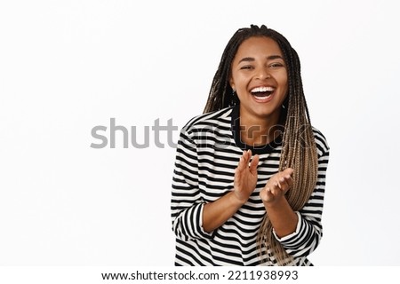 Happy black girl laughing and smiling, applausing, clap hands and looking joyful, standing over white background