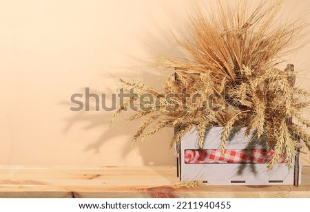 Ears of rye and wheat in a wooden box on a rustic table with space for text, modern bakery and harvest concept, healthy natural food,