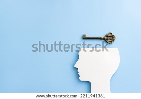 Silhouette of human head and bronze key on blue background. Minimal mental health or psychotherapy concept. Сopy space Royalty-Free Stock Photo #2211941361