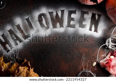 halloween concept, the inscription "HALLOWEEN" on dark background with pumpkin with bats top view