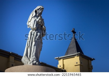 Beautiful statue of Santa Rita de Cassia, with church tower and blue sky in the background