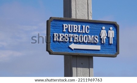 Close-up of a wooden Public Restrooms sign against a blue sky at Stearns Wharf in Santa Barbara, California, USA