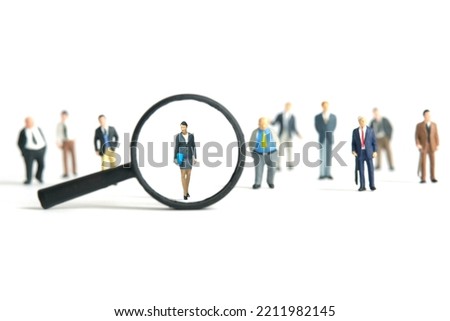 Miniature people toy figure photography. Women leader search. A businesswoman standing in the middle of male people crowd with magnifier glass. Isolated on white background. Image photo