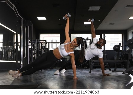 Strong man and woman holding dumbbells in plank position at the gym Royalty-Free Stock Photo #2211994063