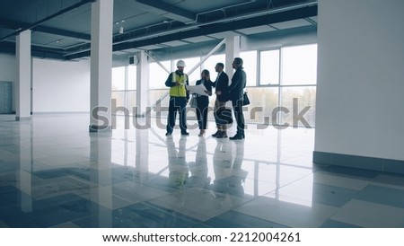 Business team are talking and looking around modern glass wall building standing inside discussing construction together. Real estate and commerce concept. Royalty-Free Stock Photo #2212004261