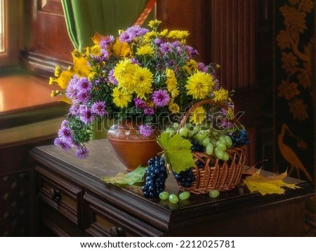 Still life with basket of grapes and bouquet of autumn flowers