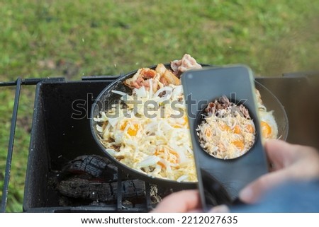 natural light. barbecue. a frying pan is used for cooking. fire. firewood. the girl takes pictures on the phone