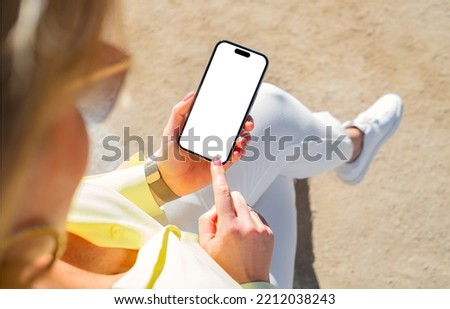 Woman sitting outside and using mobile phone with empty white screen