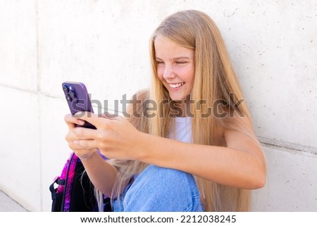 Smiling teenage girl using mobile phone outdoors