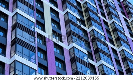 The facade of the building in purple,geometric patterns from windows and balconies, the colored wall of a modern multi-storey residential building, the abstract texture of the facade of the house. 