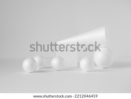 Composition of various 3d geometric shapes in white. Polystyrene balls, cube, cone, on isolated light background. Concept of visual aids, podiums