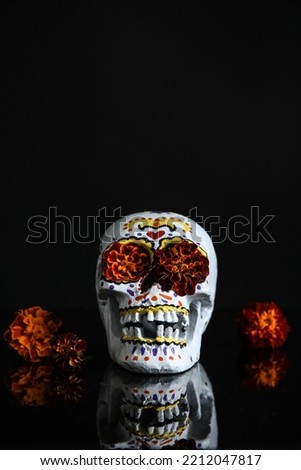 Painted skull for Mexico's Day of the Dead (El Dia de Muertos) with marigold flowers on black background