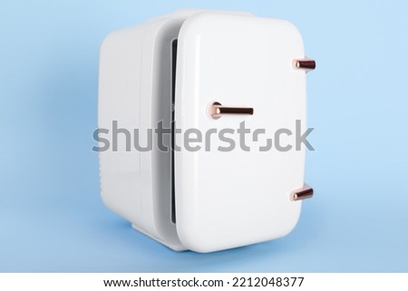 Small cosmetic refrigerator on blue background