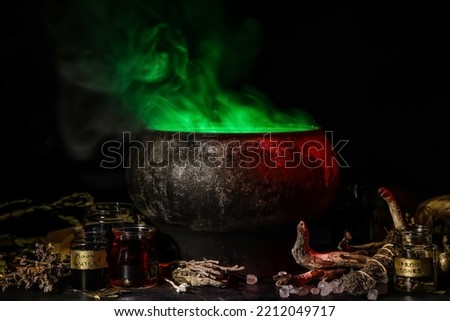 Witch's cauldron with potion and magic attributes for ritual on dark background Royalty-Free Stock Photo #2212049717