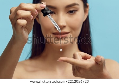 Portrait of pretty woman dripping serum on her finger. Royalty-Free Stock Photo #2212056723