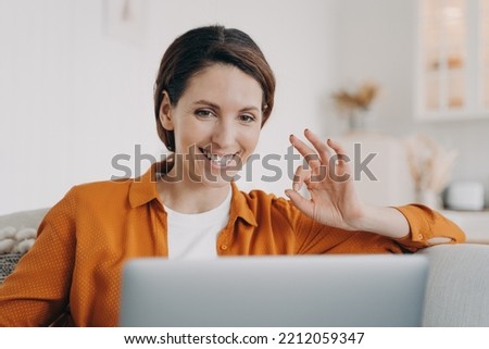 Smiling hispanic woman talking by video call at laptop, agree with friend, showing okay yes gesture. Happy female freelance worker makes ok sign, approving customer's work task, accepting project.