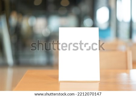 Menu frame with white blank screen on wooden table in restaurant or cafe on bokeh background.