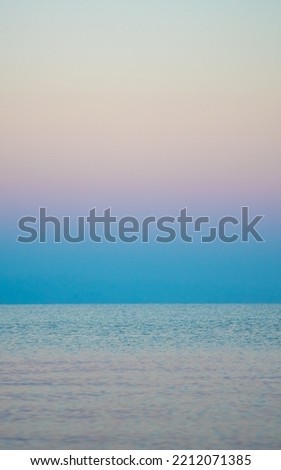 The surface of the water in the Issyk Kul mountain lake in Kyrgyzstan at sunset.Pastel and soft tones of water and sky against the background of mountains.