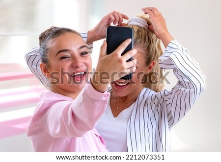 Two young women taking a selfie bursting out laughing-light and blurry background.