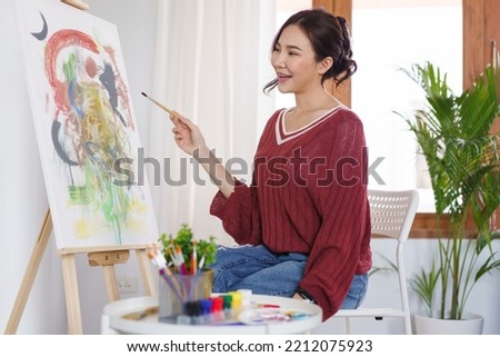 Creative of art concept, Young asian woman using paintbrush to drawing on canvas in the art studio.
