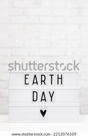 Earth day concept - lightbox with earth day words, copy space over white brick wall background