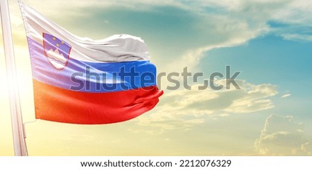 Waving Flag of Slovenia in Blue Sky. The symbol of the state on wavy cotton fabric.