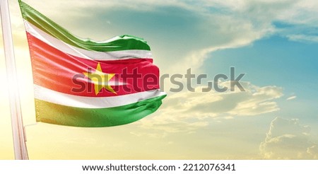 Waving Flag of Suriname in Blue Sky. The symbol of the state on wavy cotton fabric.