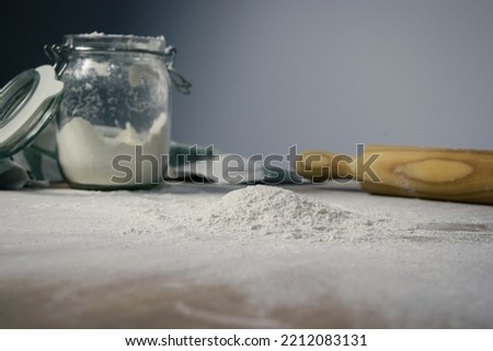 wallpaper with flour spread on the table and in the background a mixer, a jar and a rag