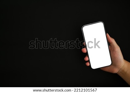Close up view of hand holding mock up smart phone with empty screen isolated on black background