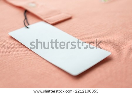 Blank white clothes tag label on pink fabric texture background