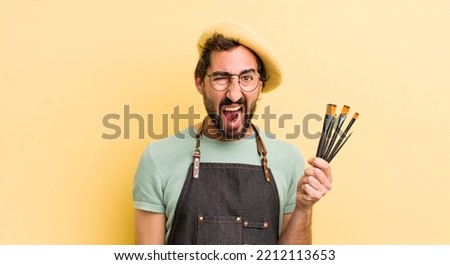 young crazy artist with brushes and wearing an apron and a beret 