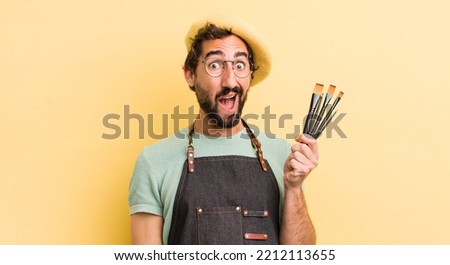 young crazy artist with brushes and wearing an apron and a beret 