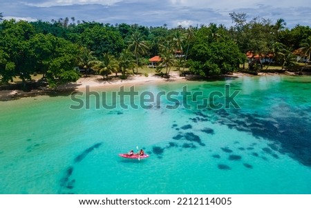 Men and women in a Kayak peddling in the turquoise-colored ocean of the tropical Island of Koh Mak Thailand. men and women in kayaks at a blue ocean and white beach with palm trees in Thailand Royalty-Free Stock Photo #2212114005
