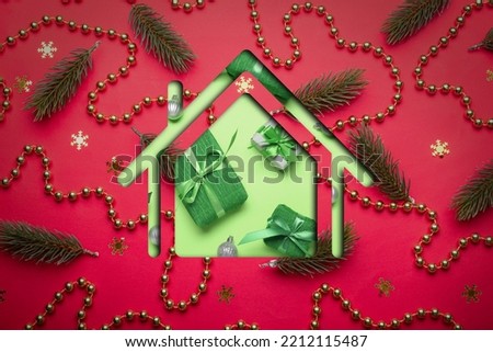 House shape with Christmas decor and gifts on red background. Concept of real estate