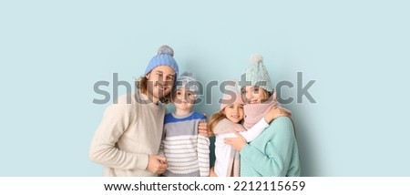 Happy family in winter clothes on light blue background
