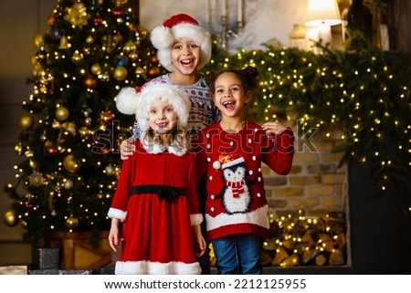 Children sing a song standing by the fireplace on Christmas Eve. Royalty-Free Stock Photo #2212125955